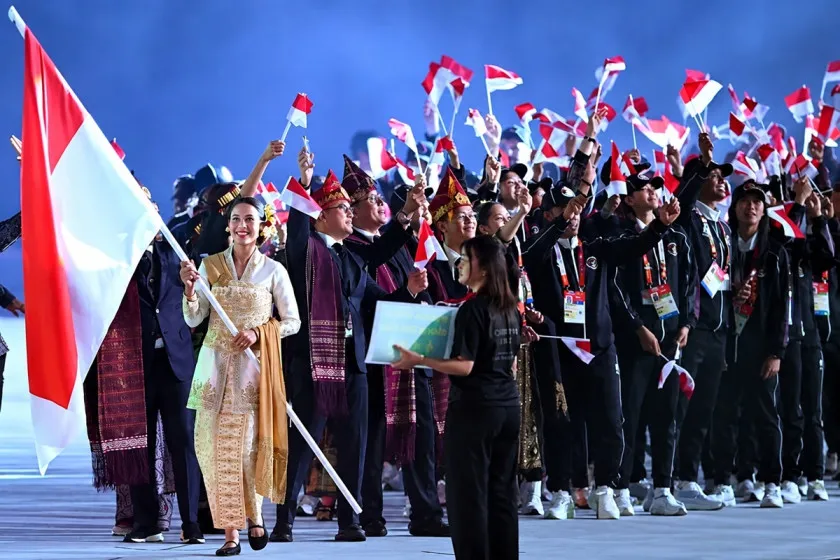 Pebasket Dewa Ayu membawa bendera Merah Putih pada defile Indonesia di Asian Games 2026